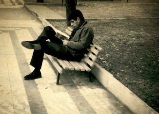 Un hombre lee un libro en la plaza