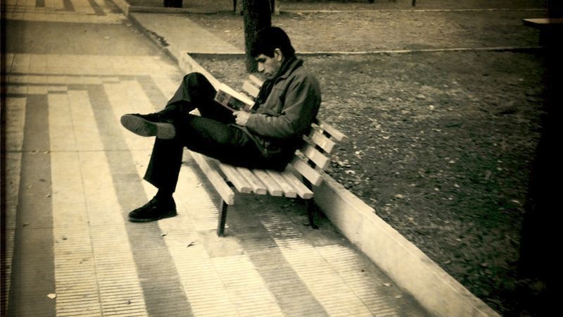 Un hombre lee un libro en la plaza